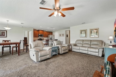 Living area with light colored carpet, a textured ceiling, ceiling fan, and recessed lighting