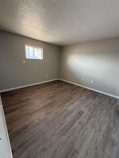 Empty room with wood finished floors and a textured ceiling