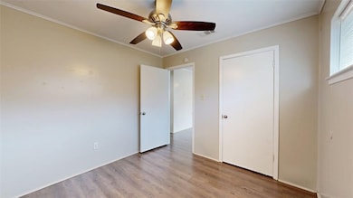 Unfurnished bedroom with ornamental molding, light wood-style floors, and ceiling fan