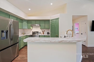 Kitchen featuring appliances with stainless steel finishes, green cabinetry, under cabinet range hood, dark wood finished floors, and lofted ceiling