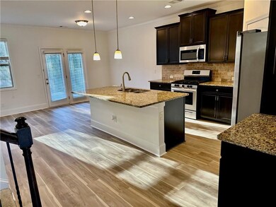 Kitchen with appliances with stainless steel finishes, light stone countertops, ornamental molding, decorative backsplash, and light wood-type flooring