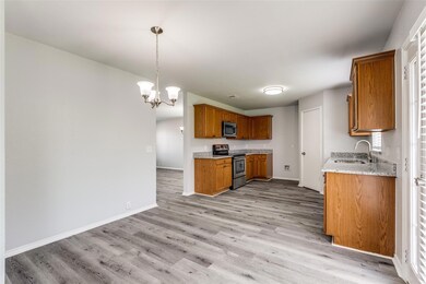 Kitchen with appliances with stainless steel finishes, sink, light hardwood / wood-style floors, decorative light fixtures, and light stone countertops