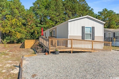 View of front of property featuring a wooden deck, view of scattered trees, and board and batten siding