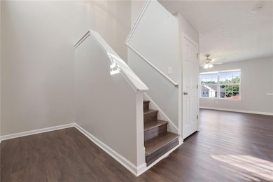 Stairway with wood finished floors, baseboards, and ceiling fan