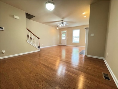 Empty room with wood finished floors, ceiling fan,