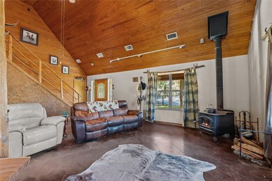 Living room with high vaulted ceiling, a wood stove, and wooden ceiling