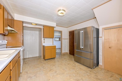 Kitchen featuring freestanding refrigerator, light countertops, under cabinet range hood, and white electric range