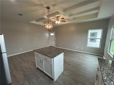 Kitchen with open floor plan, coffered ceiling, dark wood-type flooring, white cabinets, and hanging light fixtures