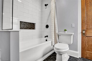 Bathroom featuring tile patterned floors, toilet, and shower / bath combination with curtain