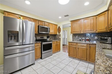 Kitchen with appliances with stainless steel finishes, brown cabinetry, light stone countertops, light tile patterned flooring, and tasteful backsplash