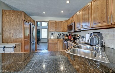 Kitchen featuring brown cabinets, stainless steel appliances, decorative backsplash, a textured ceiling, and recessed lighting