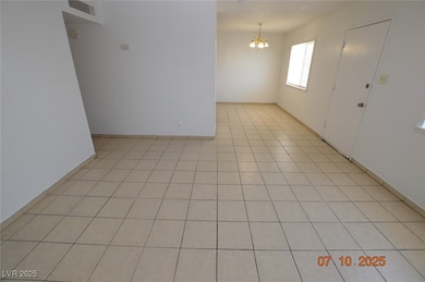 Empty room featuring a chandelier and light tile p