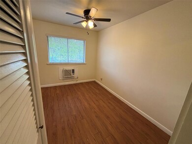 Spare room with an AC wall unit, dark wood-style 