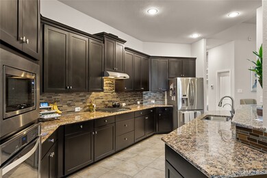 This kitchen is by far any chef’s dream! This spacious kitchen features high ceilings, dark stained wood cabinets, granite countertops, SS appliances, modern tile backsplash, recessed lighting, extended counter space, granite kitchen island with double sink and space for breakfast bar, and a walk-in pantry all overlooking your huge family room.
