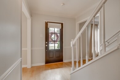 Welcoming entry with hardwood floor and front stai