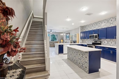 Kitchen featuring blue cabinetry, appliances with stainless steel finishes, light countertops, a peninsula, and recessed lighting
