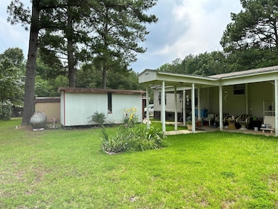 Back of property featuring a storage unit, a lawn,
