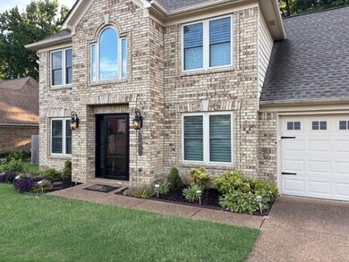 View of front facade featuring a shingled roof, an attached garage, a front lawn, and brick siding