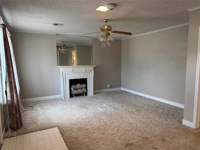 Unfurnished living room featuring light colored carpet, a textured ceiling, crown molding, a fireplace, and ceiling fan