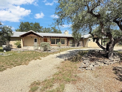View of front of property featuring a chimney, a metal roof, circle driveway, and board and batten siding