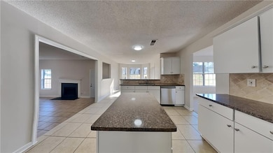 Kitchen featuring dishwasher, light tile patterned flooring, healthy amount of natural light, and a textured ceiling