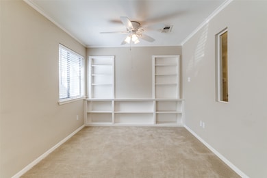 Unfurnished room with light colored carpet, ornamental molding, ceiling fan, and built in features