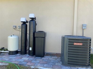 Exterior view of central AC unit, stucco siding, a water pressure tank, and a water softener system