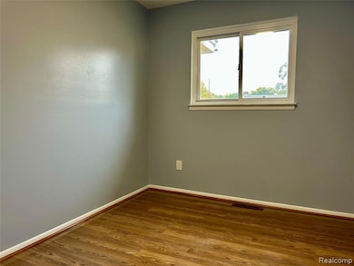 Unfurnished room featuring wood finished floors and baseboards