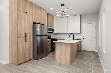 Kitchen featuring stainless steel appliances, modern cabinets, wood finish floors, light brown cabinetry, and recessed lighting