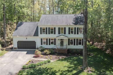 Colonial home featuring a garage and a front lawn