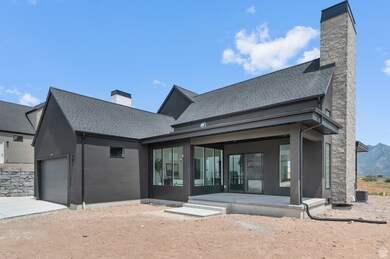 Back of property with a chimney, roof with shingles, an attached garage, and concrete driveway