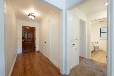 Corridor with crown molding and light hardwood / w