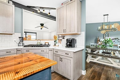 Kitchen featuring gas stovetop, tasteful backsplash, ceiling fan, dark wood-type flooring, and gray cabinetry