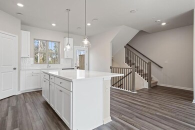 Kitchen with dark wood finished floors, a center island, light countertops, white cabinets, and recessed lighting