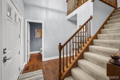 Stairway with hardwood / wood-style flooring and a towering ceiling