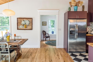 Kitchen featuring stainless steel fridge, decorative backsplash, light wood-style floors, butcher block counters, and vaulted ceiling
