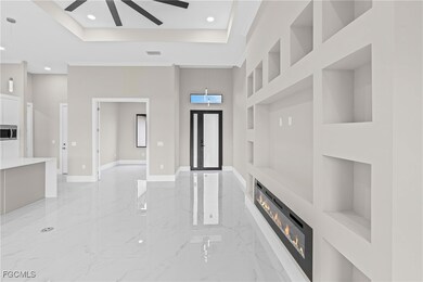 Unfurnished living room featuring built in features, light marble finish flooring, a raised ceiling, and recessed lighting