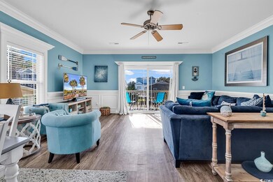 Living area with plenty of natural light, ceiling fan, a wainscoted wall, wood finished floors, and crown molding