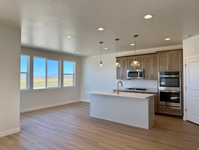 Kitchen featuring an island with sink, pendant lighting, recessed lighting, a textured ceiling, and appliances with stainless steel finishes
