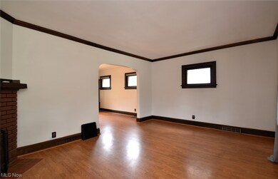 Empty room with light hardwood flooring, ornamental molding, and brick wall