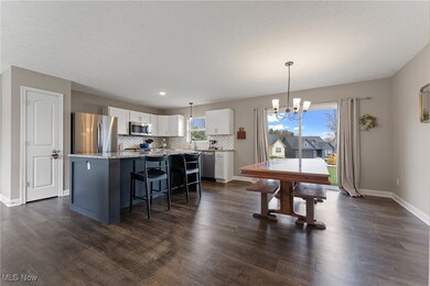 Dining space featuring a textured ceiling, dark wood-style flooring, a notable chandelier, and baseboards