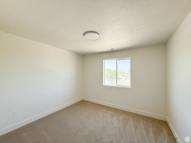 Spare room with light carpet and a textured ceiling