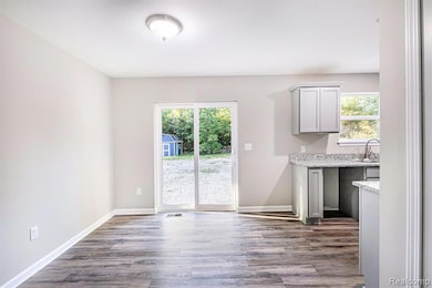 Unfurnished dining area featuring dark wood-style flooring and baseboards
