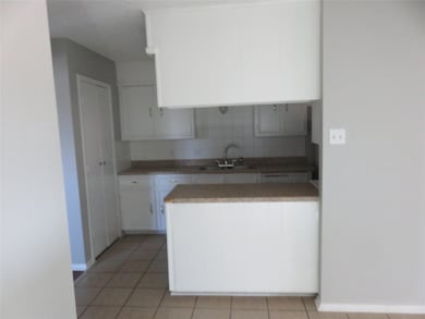 Kitchen featuring light tile flooring, sink, tasteful backsplash, and white cabinets