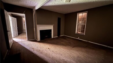 Unfurnished living room with hardwood / wood-style flooring, a fireplace, and baseboards
