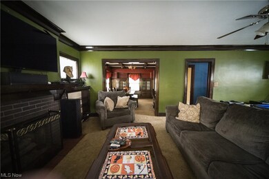Living room featuring ceiling fan, crown molding, a fireplace, and carpet flooring