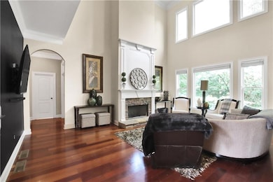 Living room with ornamental molding, a fireplace, dark wood-type flooring, a towering ceiling, and baseboards
