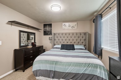 Carpeted bedroom featuring a textured ceiling and baseboards