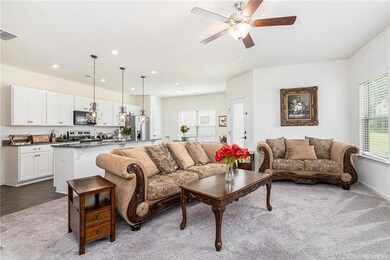 Carpeted living area with ceiling fan, recessed lighting, and baseboards