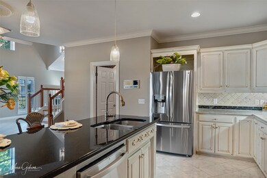 Kitchen featuring appliances with stainless steel finishes, ornamental molding, dark stone countertops, tasteful backsplash, and hanging light fixtures